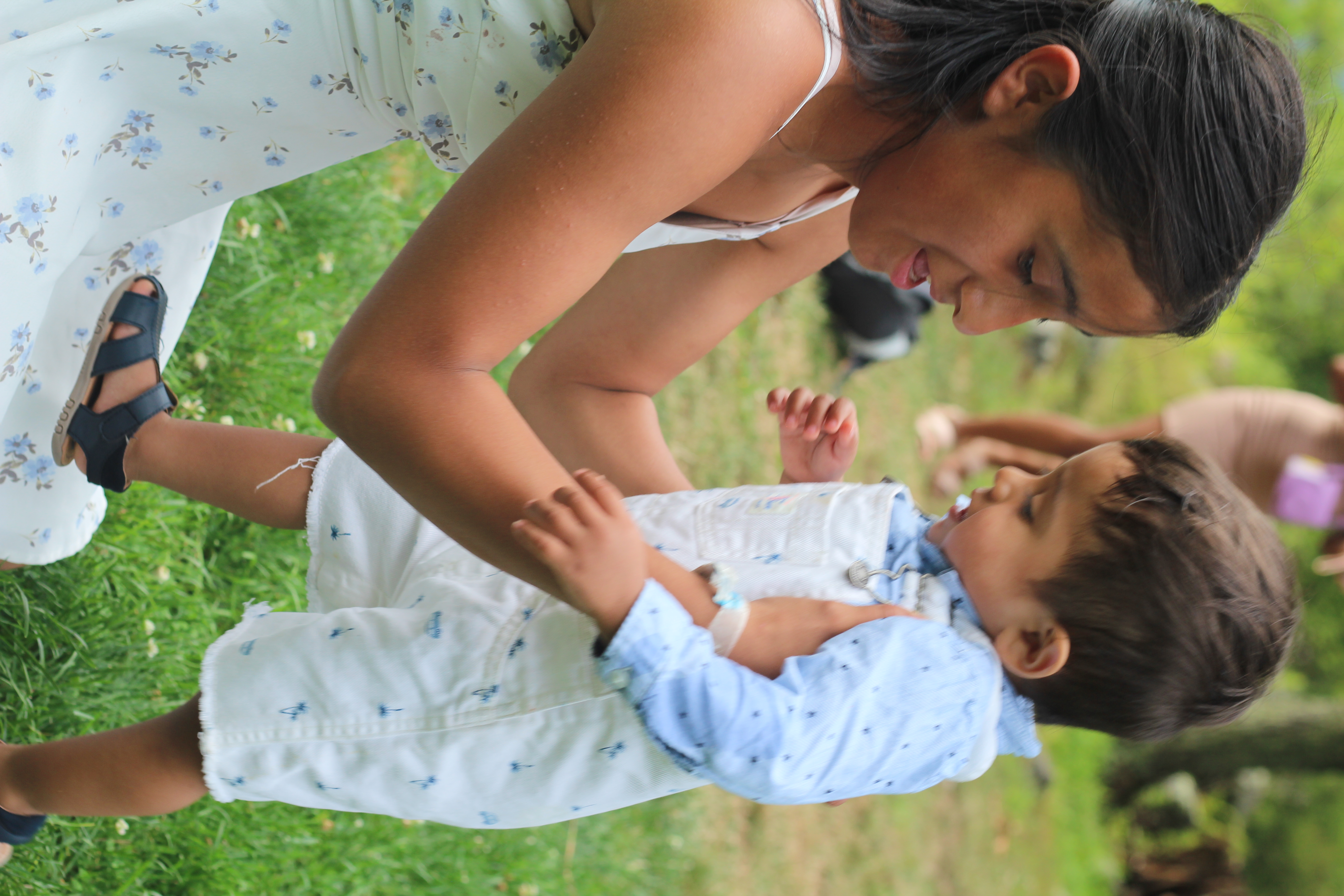 A teen mom playing with her toddler in a field